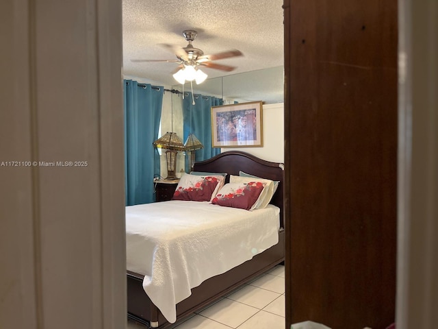 bedroom with ceiling fan, a textured ceiling, and light tile patterned floors