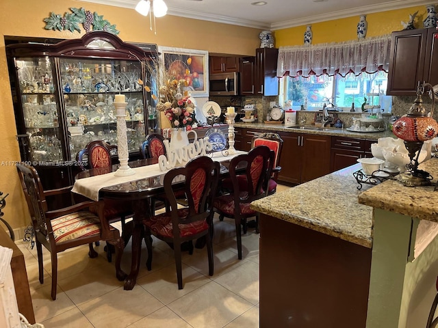 kitchen with light tile patterned floors, ornamental molding, backsplash, and sink