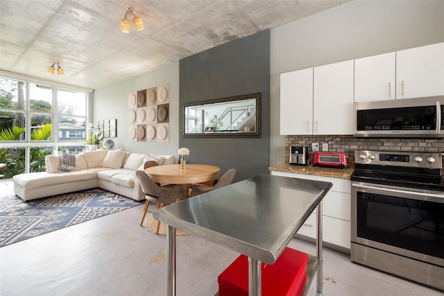 kitchen with stainless steel appliances, a kitchen breakfast bar, decorative backsplash, and white cabinets