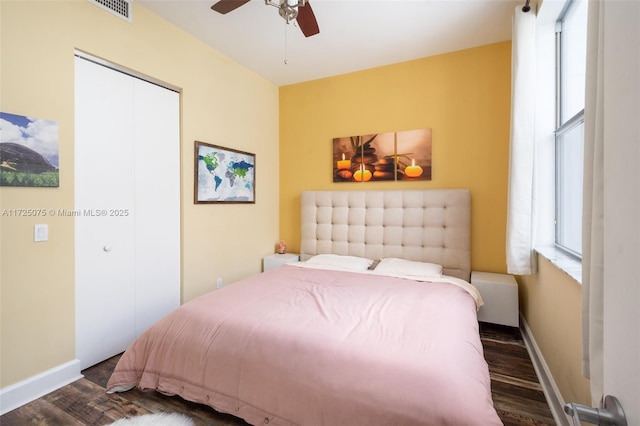 bedroom with dark wood-type flooring, ceiling fan, and a closet