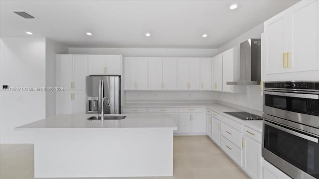 kitchen with stainless steel appliances, a kitchen island with sink, and wall chimney exhaust hood