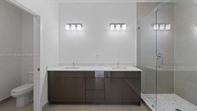 bathroom featuring toilet, tile patterned flooring, a shower with door, and vanity