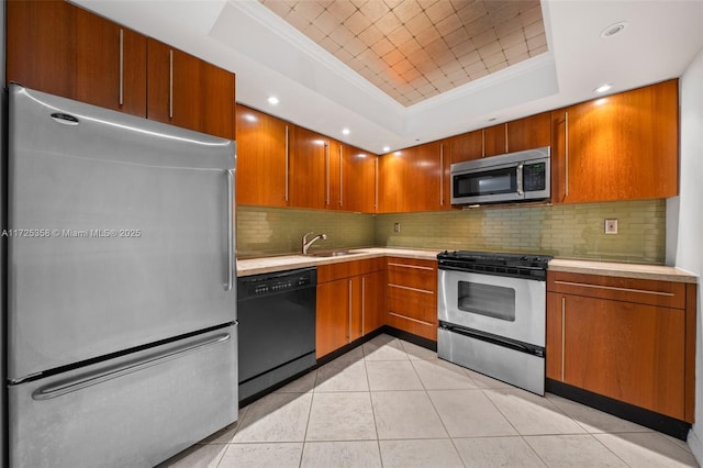 kitchen featuring a raised ceiling, light tile patterned floors, crown molding, appliances with stainless steel finishes, and sink