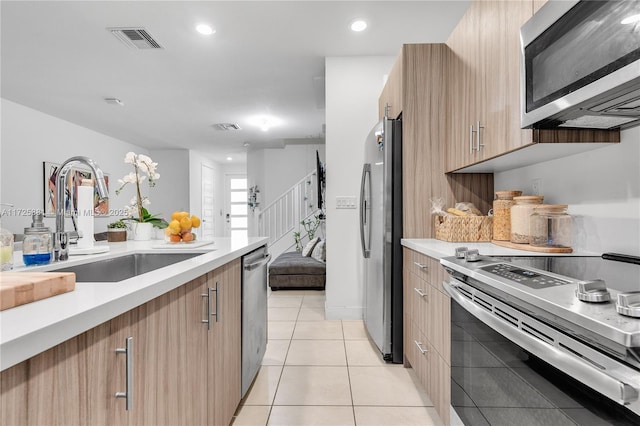 kitchen with appliances with stainless steel finishes, light tile patterned floors, and sink