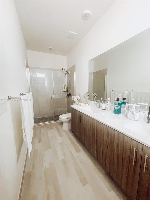 bathroom with toilet, vanity, a shower with shower door, and hardwood / wood-style floors