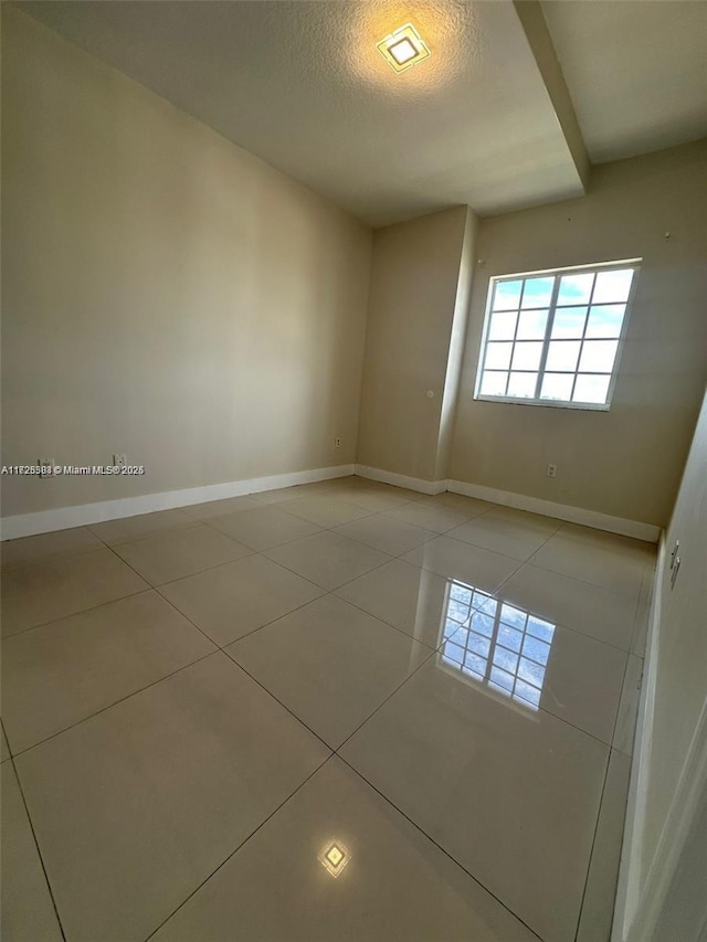 empty room featuring a textured ceiling and tile patterned flooring