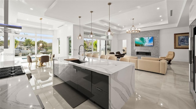 kitchen with a spacious island, pendant lighting, sink, and a raised ceiling