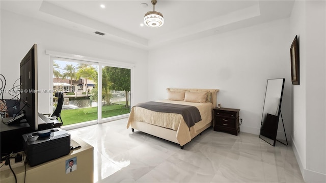 bedroom with a raised ceiling and access to outside