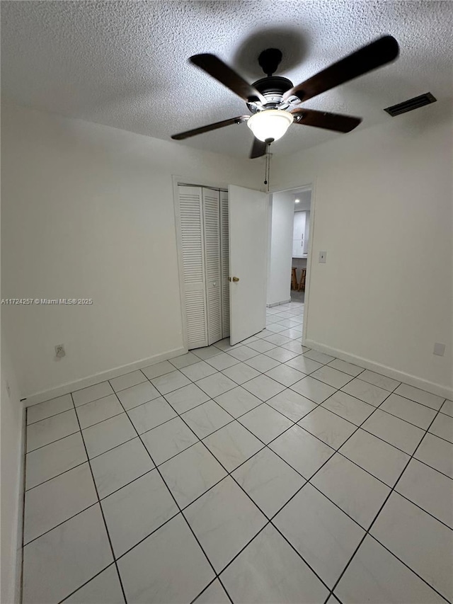 tiled empty room with a textured ceiling and ceiling fan