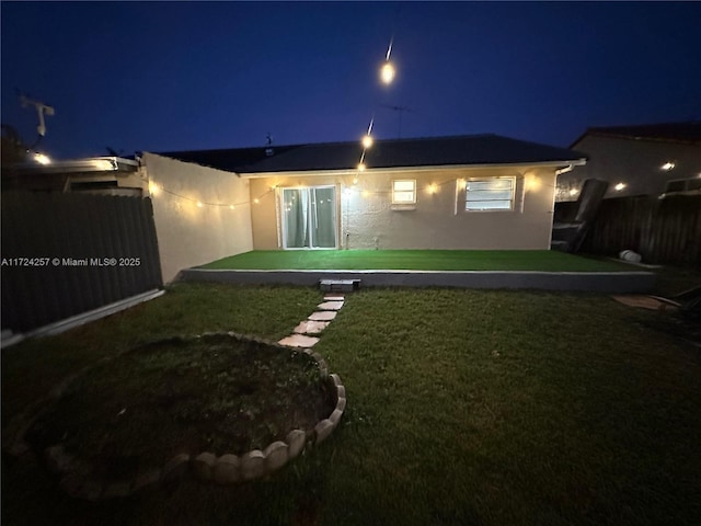 back house at twilight with a lawn