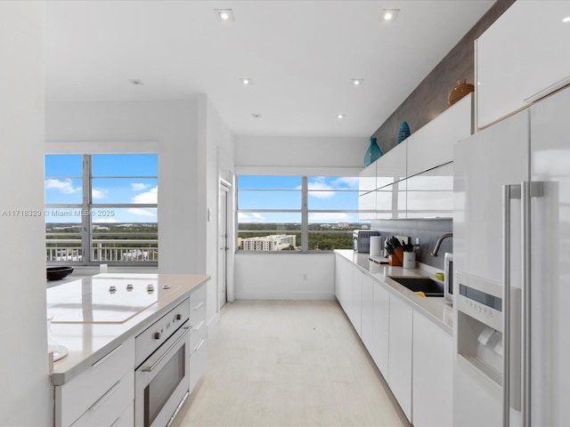 kitchen featuring white appliances, white cabinets, and sink