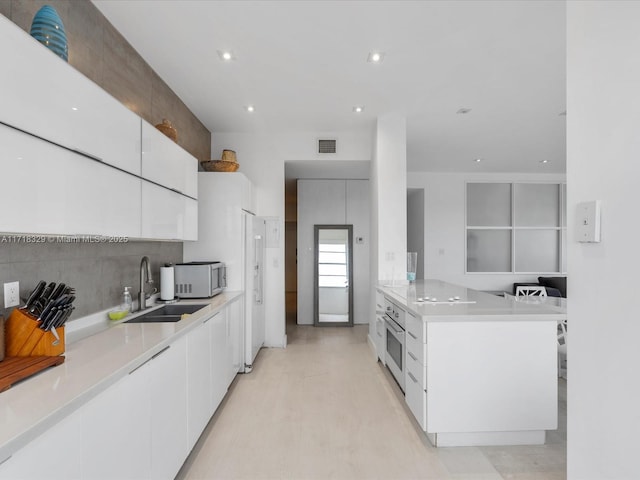 kitchen with white cabinets, stainless steel oven, and sink