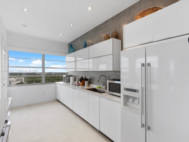 18011 Biscayne Blvd Unit Ph05, Aventura, FL 33160 - kitchen with high end white fridge, white cabinetry, tasteful backsplash, and sink