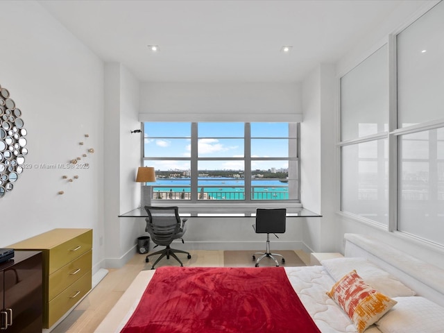 bedroom featuring light wood-type flooring and a water view