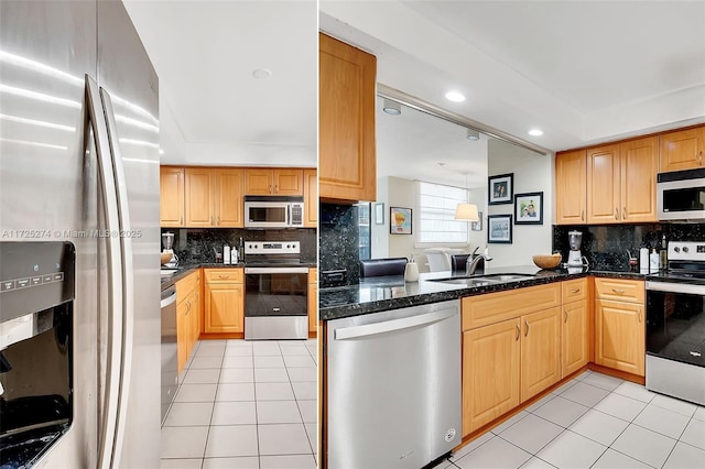 kitchen with kitchen peninsula, light tile patterned floors, appliances with stainless steel finishes, dark stone countertops, and sink