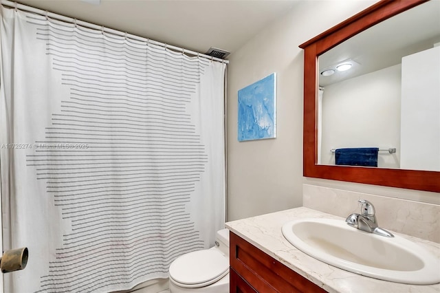 bathroom featuring toilet, vanity, and walk in shower