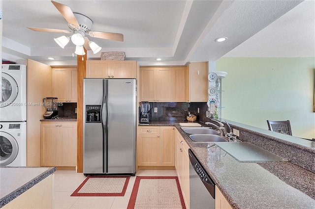 kitchen with sink, stacked washing maching and dryer, light brown cabinets, light tile patterned flooring, and appliances with stainless steel finishes