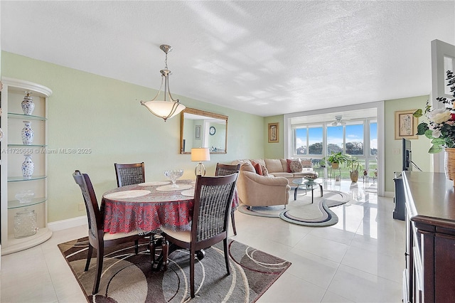 tiled dining area with a textured ceiling and ceiling fan