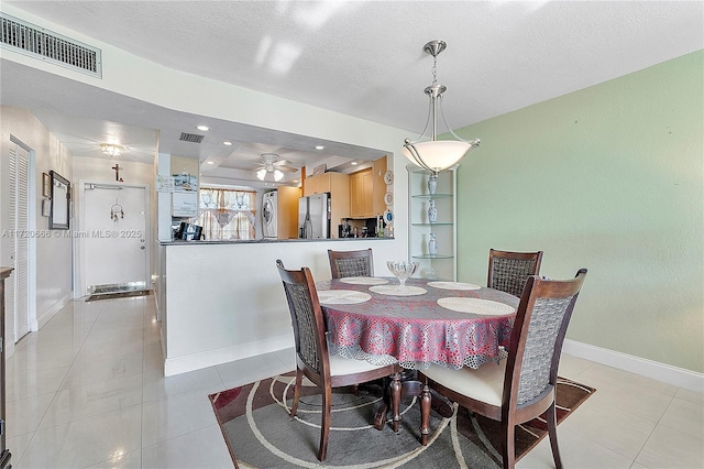 tiled dining area with a textured ceiling and ceiling fan