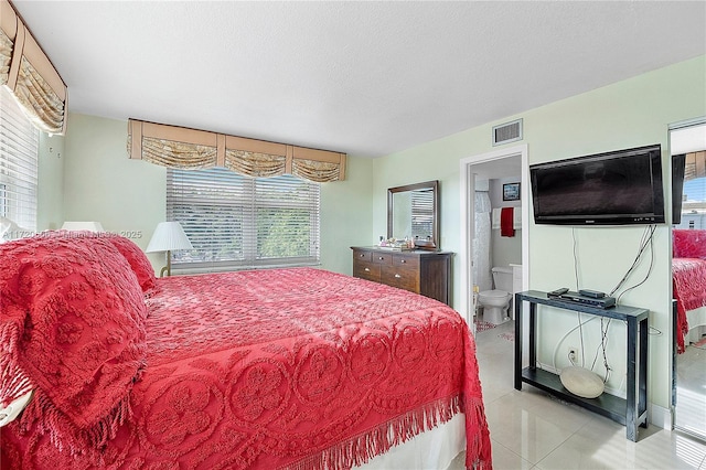 bedroom featuring ensuite bathroom and light tile patterned floors