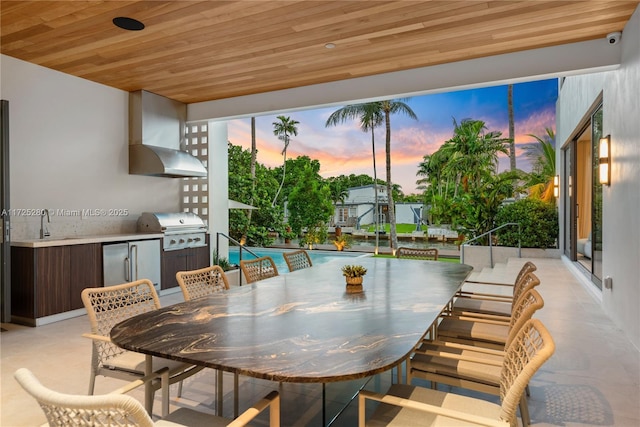 patio terrace at dusk featuring an outdoor kitchen and a grill