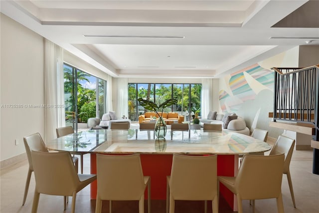 tiled dining space featuring a raised ceiling and plenty of natural light