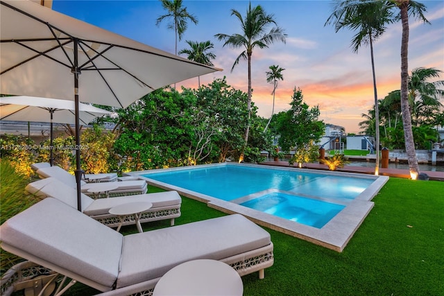 pool at dusk featuring a lawn