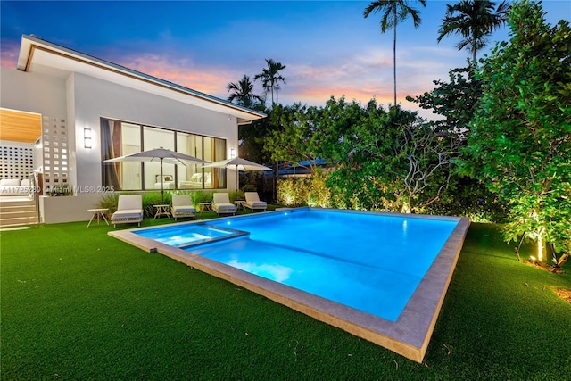 pool at dusk featuring a yard