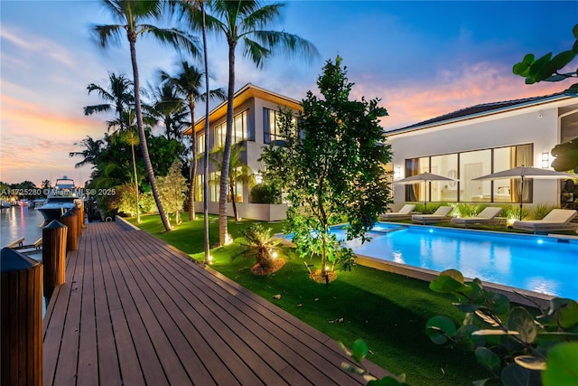 pool at dusk with a lawn and a water view