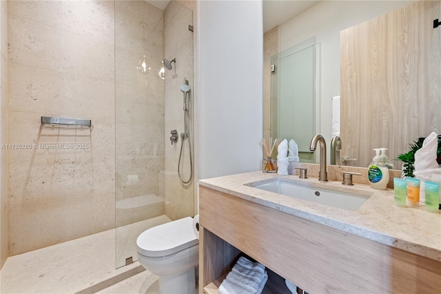 bathroom featuring a tile shower, vanity, and toilet