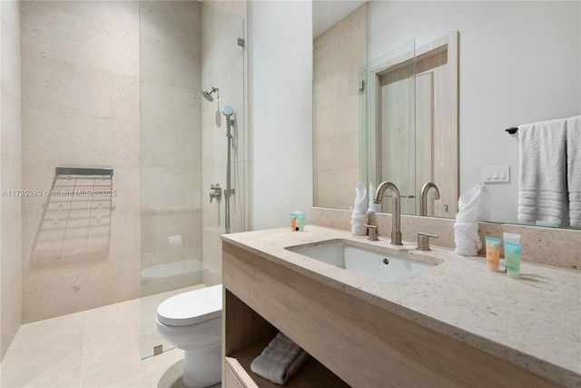 bathroom featuring toilet, tile patterned flooring, a tile shower, and vanity