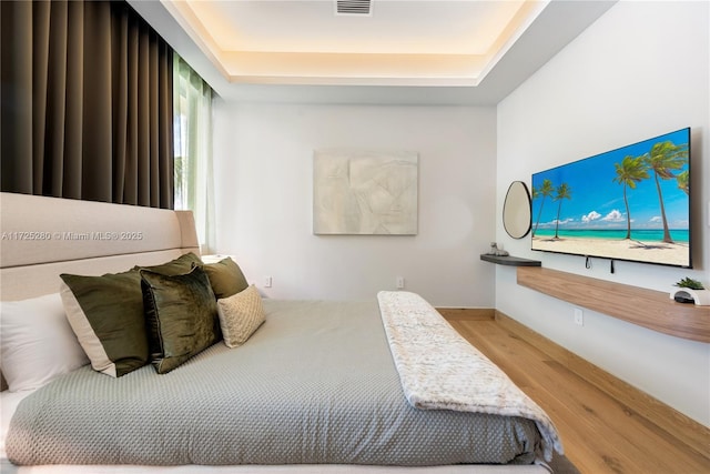 bedroom featuring a raised ceiling and hardwood / wood-style flooring