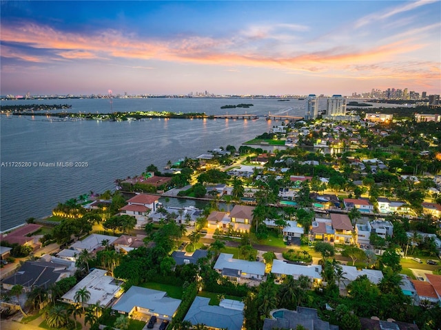 aerial view at dusk featuring a water view