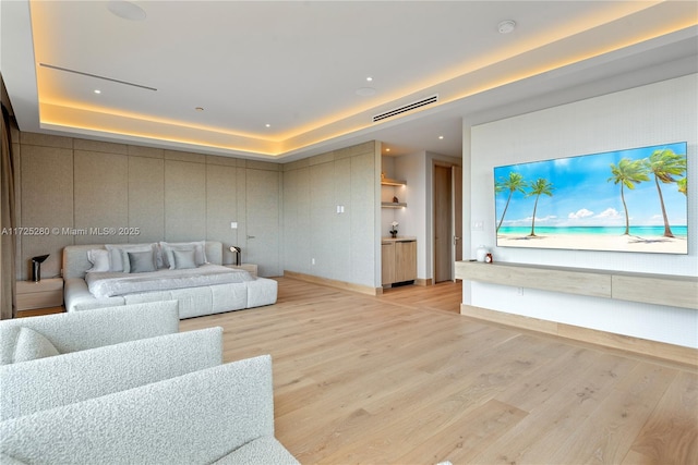 living room featuring light wood-type flooring and a raised ceiling