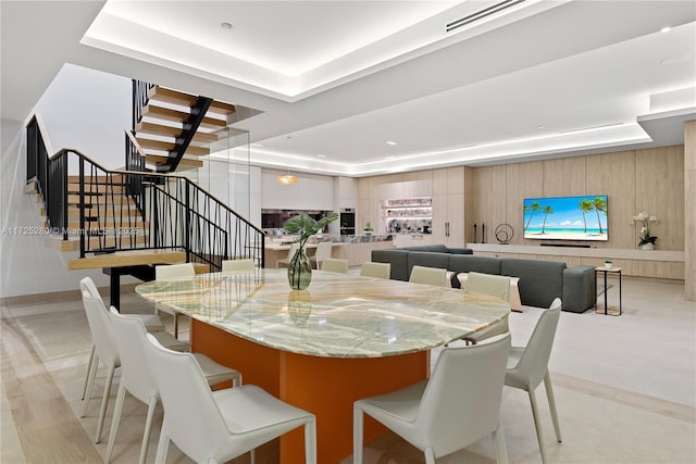 dining area featuring a raised ceiling and wood walls