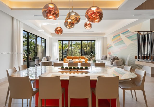 tiled dining room with a healthy amount of sunlight and a tray ceiling