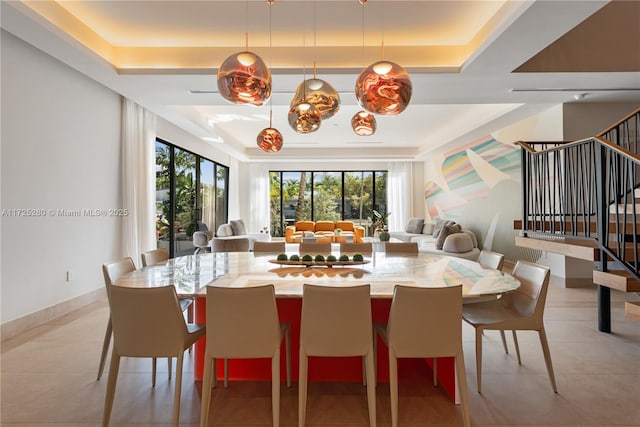 dining room featuring a raised ceiling and light tile patterned flooring