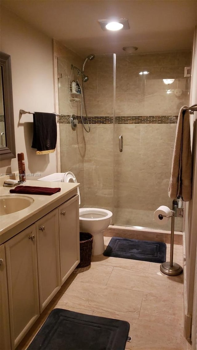 bathroom featuring toilet, tile patterned flooring, a shower with door, and vanity