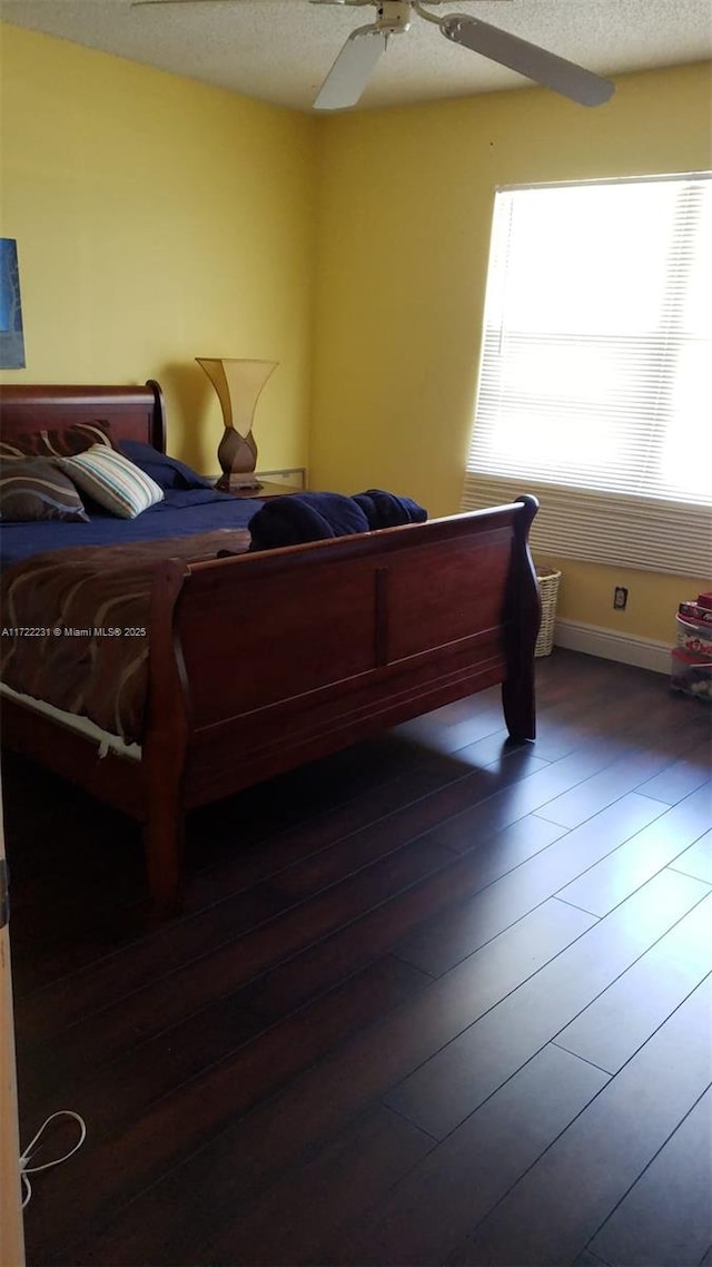 bedroom featuring ceiling fan, dark hardwood / wood-style flooring, and a textured ceiling