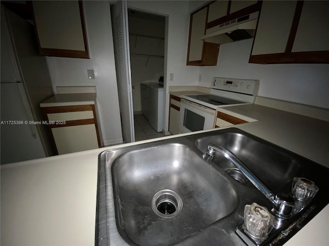 kitchen featuring white range with electric cooktop, washing machine and dryer, and sink