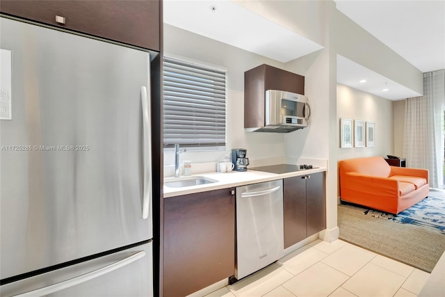 kitchen with dark brown cabinetry, appliances with stainless steel finishes, light tile patterned flooring, and sink