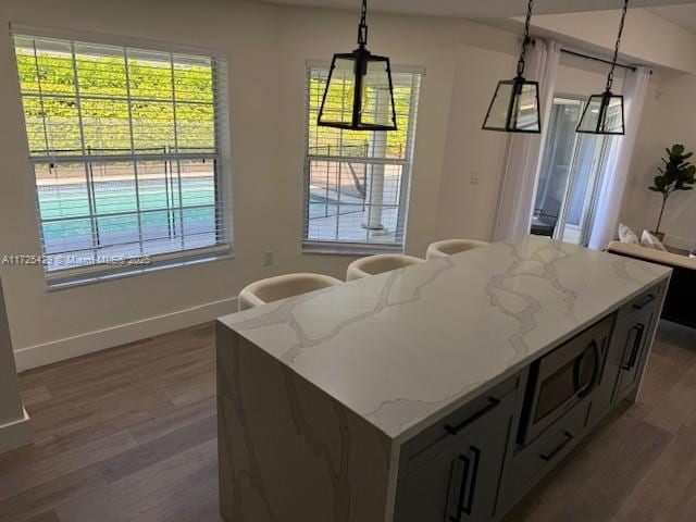 kitchen featuring light stone countertops, a kitchen island, pendant lighting, and dark hardwood / wood-style floors