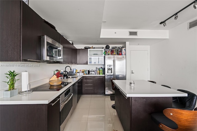 kitchen with sink, light tile patterned floors, dark brown cabinetry, rail lighting, and black appliances