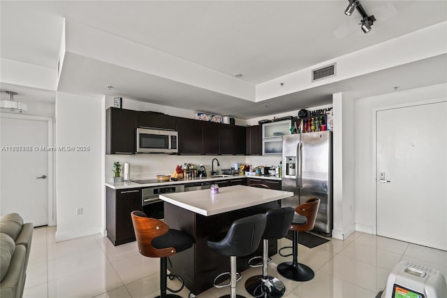 kitchen featuring a kitchen island, a breakfast bar area, light tile patterned floors, and appliances with stainless steel finishes