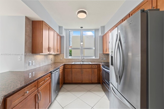 kitchen featuring stainless steel appliances, light tile patterned floors, decorative backsplash, dark stone countertops, and sink