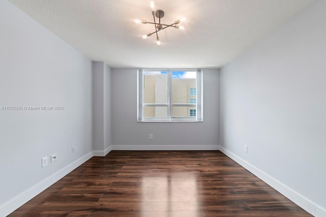 unfurnished room featuring a textured ceiling, dark hardwood / wood-style flooring, and an inviting chandelier