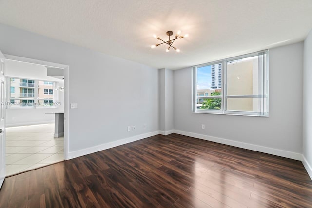 unfurnished room with an inviting chandelier and dark hardwood / wood-style floors