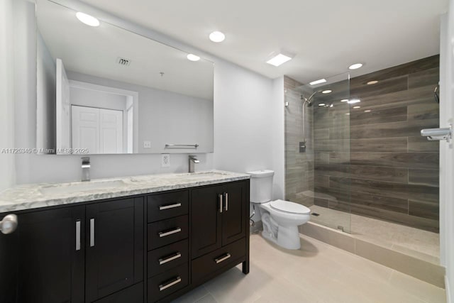 bathroom with toilet, a tile shower, and vanity