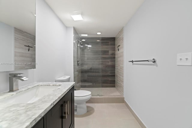 bathroom with toilet, tile patterned floors, tiled shower, and vanity