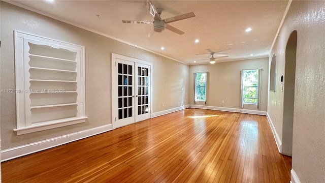 spare room with wood-type flooring, ceiling fan, ornamental molding, french doors, and built in shelves